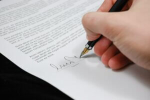  A person signs their signature on a legal document with a fountain pen.